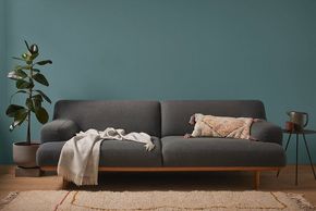 Ein graues Sofa mit Kissen und einer Decke
